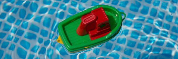 Kleines Plastikspielzeugboot schwimmt in einem Swimmingpool. Panorama-Bild - Foto, Bild