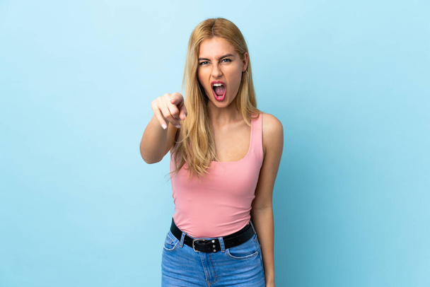 Young Uruguayan blonde woman over isolated blue background frustrated and pointing to the front - Φωτογραφία, εικόνα