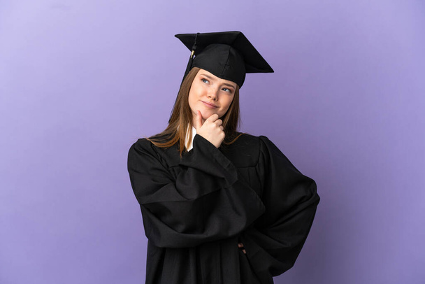 Young university graduate over isolated purple background and looking up - Photo, Image