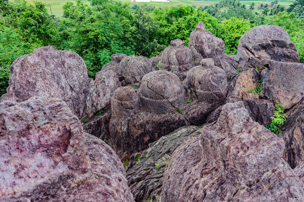 πολύ μεγάλη πέτρα βρίσκεται στην κορυφή των λόφων με δέντρα πρασίνου κατά τη διάρκεια της ημέρας. - Φωτογραφία, εικόνα