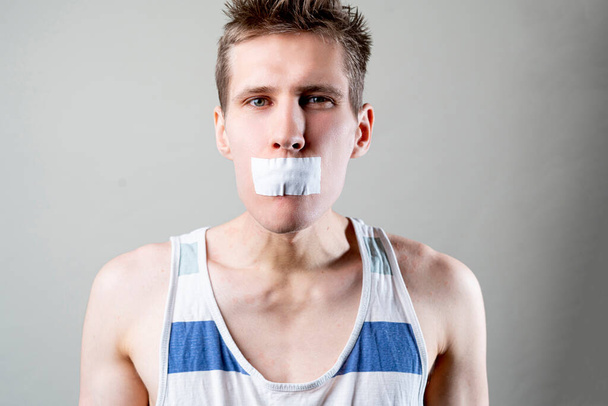 ein Mann mit Klebeband schließt den Mund, hört auf zu reden und schaltet ab, Zensurkonzept, - Foto, Bild