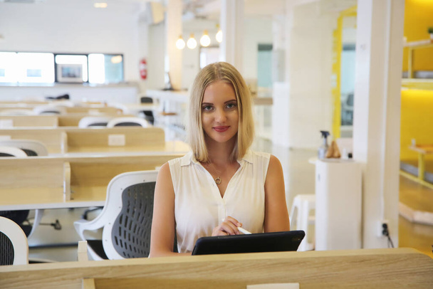 Una mujer sonriente que usa una computadora portátil en el lugar de trabajo para pequeñas empresas que buscan involucrar al público y escalar la creación de contenido puede adoptar nueva tecnología de marketing en el espacio de trabajo. Concepto freelancer. - Foto, Imagen