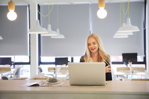 Smiling woman using laptop in work place for small businesses looking to engage audiences and scale content creation can adopt new marketing technology in workspace. Freelancer concept. - Photo, Image