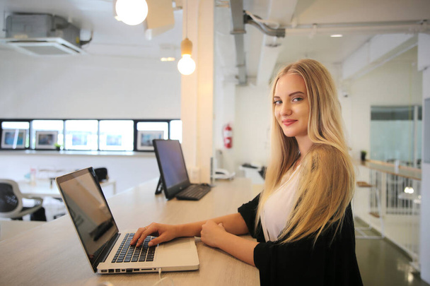 Uśmiechnięta kobieta korzystająca z laptopa w miejscu pracy dla małych firm chcących angażować odbiorców i tworzyć treści na dużą skalę może przyjąć nową technologię marketingową w miejscu pracy. Koncepcja wolnego strzelca. - Zdjęcie, obraz