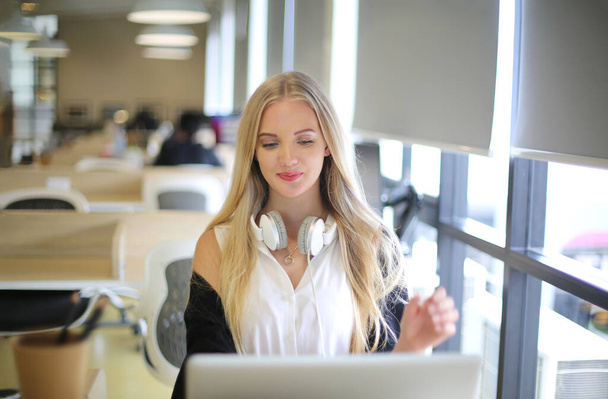 Mulher sorridente usando laptop no local de trabalho para pequenas empresas que procuram engajar o público e escala de criação de conteúdo pode adotar nova tecnologia de marketing no espaço de trabalho. Conceito de freelancer. - Foto, Imagem