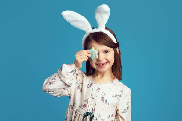 女の子はウサギの耳を身に着けています,カバー目で星形クッキー隔離された青 - 写真・画像