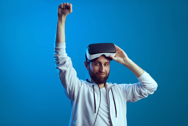 Молодий чоловік виграв важку гру, підняв руку, кулак і зняв окуляри VR
 - Фото, зображення