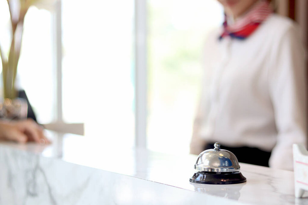 Closeup of silver bell ring on hotel reception service desk with receptionist service customer at hotel counter desk as blurred background.  - Photo, Image