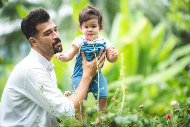family person concept, father and baby child joy playing in the outdoor nature grass flower garden, having fun and happy smiling, childhood and parent love together in summer at home - Foto, imagen