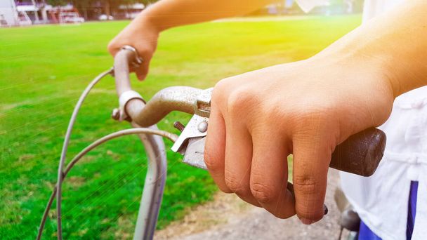 Hands are on a vintage bike handle and fingers holding the break shaft, the sunlight shines on a hand - Photo, Image