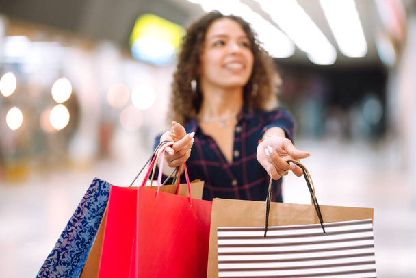 女性の手のショッピングバッグを保持を閉じます。モールで買い物をした後の若い女性。消費主義、販売、購入、ライフスタイルの概念. - 写真・画像