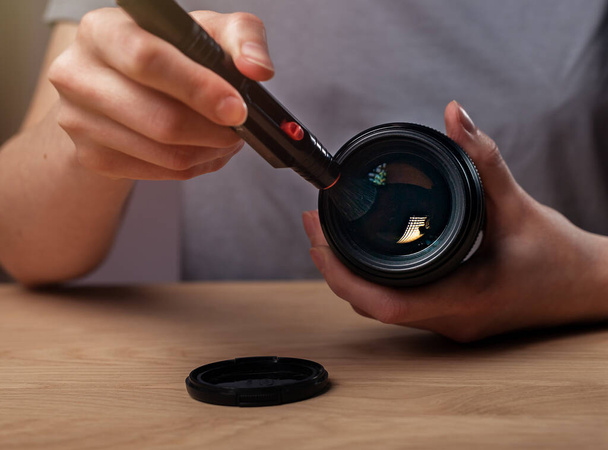 Hands closeup cleaning camera lens with black professional brush or pen, closeup, removing dust - Fotó, kép