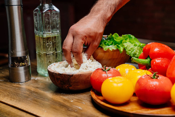 hand takes flour from a wooden bowl. ingredients for cooking.  - Foto, afbeelding