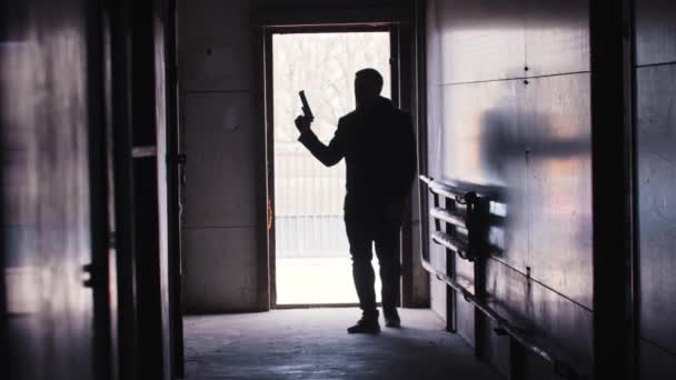 Ένας άντρας μπαίνει στο δωμάτιο κρατώντας ένα όπλο και αρχίζει να πυροβολεί - Πλάνα, βίντεο