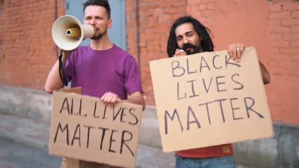 Two Caucasian men are protesting in the street with megaphones and signs - Footage, Video