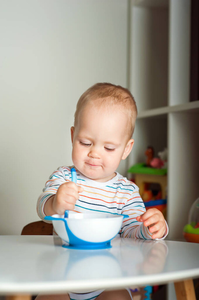 Handsome toddler sitting with plate close-up. Baby complementary feeding, food allergy, intolerance concept. - Fotografie, Obrázek