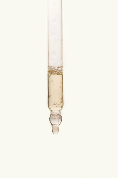 Pipette mit ätherischem Öl auf verschwommenem Blumenhintergrund - Foto, Bild