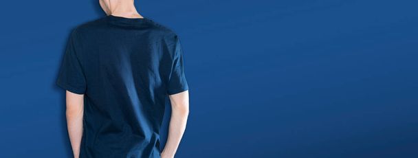 man in the dark blue t-shirt mockup and copy space against the color wall backround, no face - Fotó, kép
