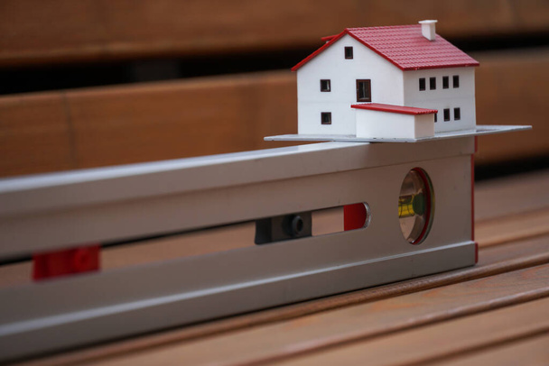 Real estate concept. House model and tubular spirit level, symbols of new building projects - Photo, Image