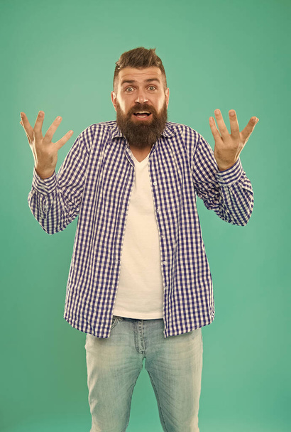 confused bearded man in casual checkered shirt on blue background, embarrassment - Фото, изображение
