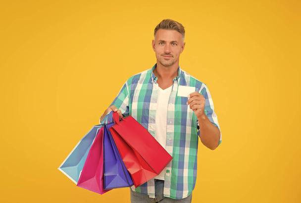 successful mature shopper man carry shopping bags and hold business or credit card, bargain sale - Фото, изображение