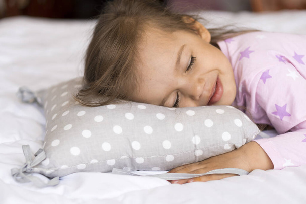 home, comfort, childhood, care, love, sweet dream- little pretty smiling happy authentic toddler sibling kid child girl in pajamas lie rest sleep on bed pillows with closed eyes soft cozy sleepy mood - Foto, Imagen