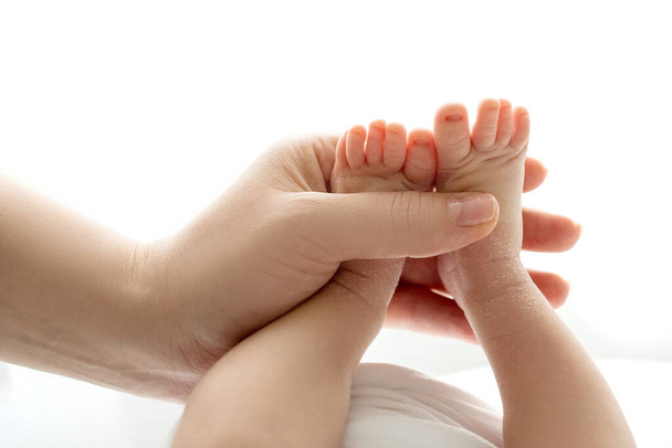 hands of parents. the legs of the newborn in the hands of mom and dad. babys legs in his hands.  - Foto, afbeelding