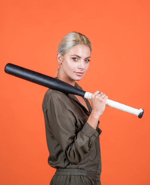 woman in uniform hold baseball or cricket bat sport game equipment on orange background, cricket - Photo, Image