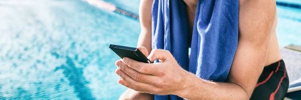 Swimmer athlete using mobile phone during triathlon race. Man at swimming pool texting sms message on cellphone training swim workout - Foto, Bild