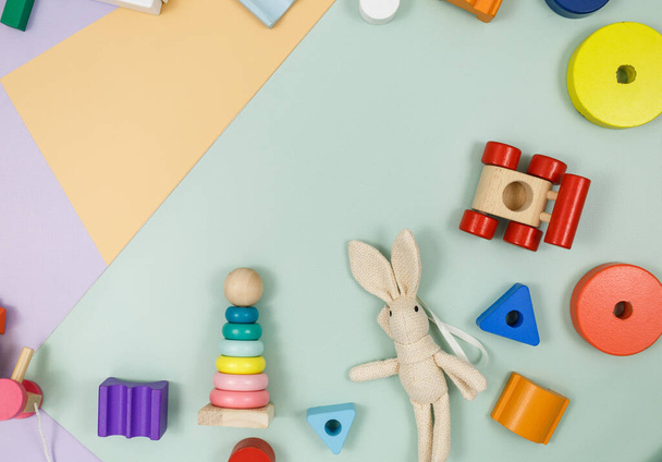 Groep veelkleurig houten speelgoed op violette, groene, beige achtergrond. Kleuter- en kinderdagverblijven, onderwijs - Foto, afbeelding