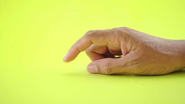 Hand gebaar van de man hand teken van het wachten teken en zet zijn vinger tafel en vingers Hij wacht of denkt iets geïsoleerd op gele achtergrond - Video