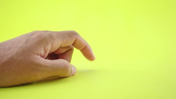Hand gebaar van de man hand teken van het wachten teken en zet zijn vinger tafel en vingers Hij wacht of denkt iets geïsoleerd op gele achtergrond - Video
