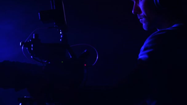 Hombres con película digital moderna movimiento cámara vista lateral. Luz azul oscura en un estudio. - Imágenes, Vídeo