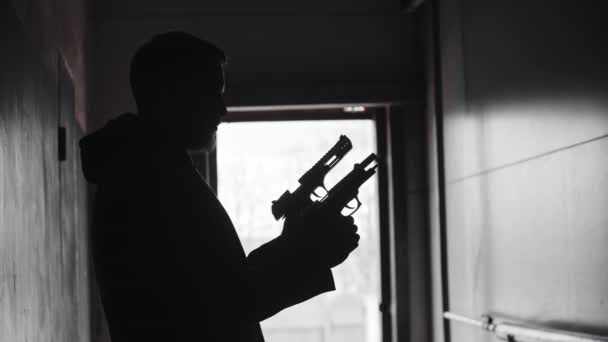 Μια σιλουέτα ανθρώπου που κρατάει δύο όπλα και σημαδεύει - Πλάνα, βίντεο