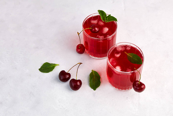 Cherry cocktail with ice and mint on a light grey background.  - Valokuva, kuva