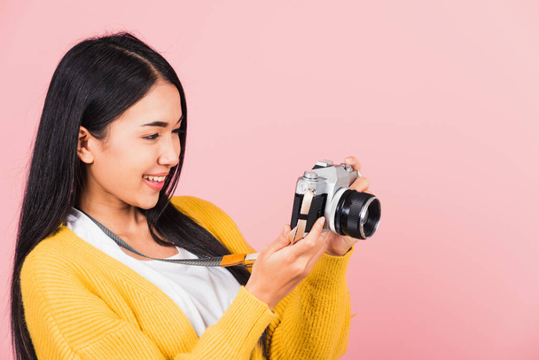 Houkutteleva energinen onnellinen aasialainen muotokuva kaunis söpö nuori nainen teini innoissaan hymyillen tilalla vintage valokuva kamera, studio ampui eristetty vaaleanpunainen tausta, matkustaja naisvalokuvaaja - Valokuva, kuva