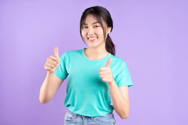 Jeune fille asiatique en chemise cyan en utilisant le téléphone sur fond violet - Photo, image