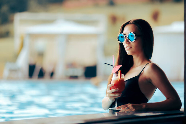 Mujer bebiendo un cóctel en la piscina durante las vacaciones de verano - Foto, Imagen