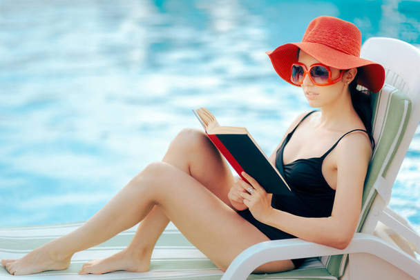 Woman Wearing a Red Sun Heat Reading a Book by the Pool  - Φωτογραφία, εικόνα