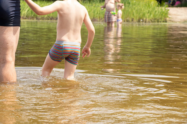 a child with dad goes into the river to swim in summer in Ukraine, swimming in the river - Photo, Image
