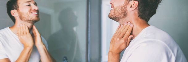 Man touching neck looking in mirror in home bathroom. Body care panoramic banner - Φωτογραφία, εικόνα