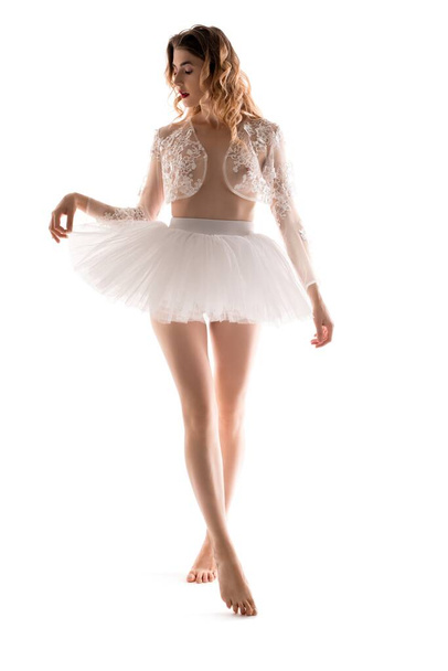 Barefoot ballerina in translucent shrug touching skirt - Zdjęcie, obraz