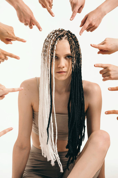 The girl is condemned by society. Original girl with African pigtails. Everyone points the finger at the girl. Strong personality vs. system - Photo, Image