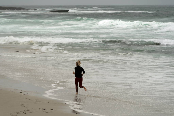 Alone female jogger in shallow water  near Big Rock Reef, La Jolla, San Diego - Photo, Image