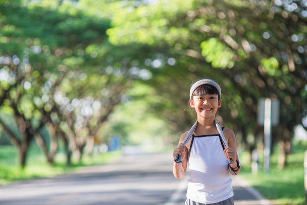 happy child girl running in the park in summer in nature. warm sunlight flare. asian little is running in a park. outdoor sports and fitness, exercise and competition learning for kid development. - Photo, Image