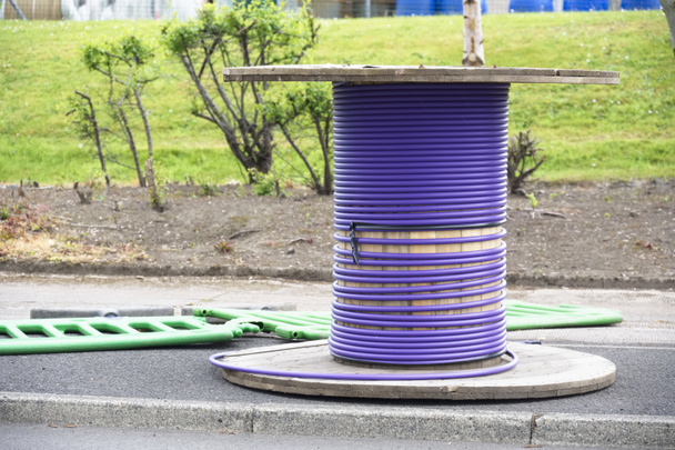 Cable púrpura y carrete de madera con cable de fibra óptica para Internet rápido listo para ser instalado - Foto, Imagen