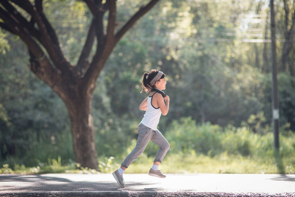 自然の中で夏に公園を走っている幸せな子供の女の子。暖かい太陽のフレア。アジアン・リトルは公園で走っています。子供の発達のための屋外スポーツとフィットネス運動と競争学習. - 写真・画像