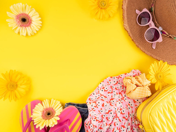 Summer fashion outfit background with straw hat, jeans, flip flops, sunglasses, handbag on yellow - Photo, Image