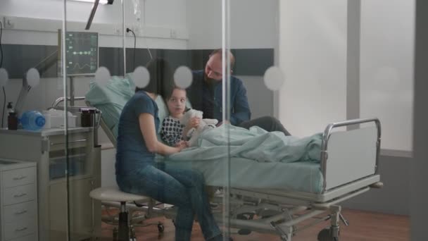 Ανήσυχοι γονείς που κάθονται με την άρρωστη κόρη τους περιμένοντας την εμπειρία ασθένειας κατά τη διάρκεια της ιατρικής εξέτασης - Πλάνα, βίντεο