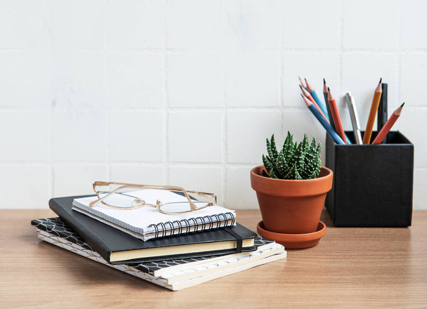 Table de bureau avec cahiers, fournitures et plantes d'intérieur - Photo, image